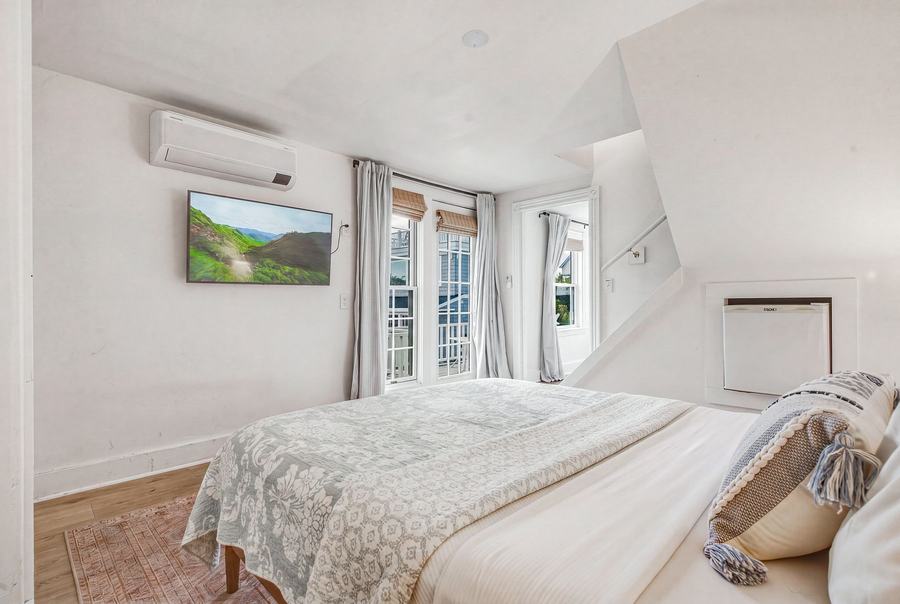 Bright king bedroom with a wall-mounted TV and coastal décor