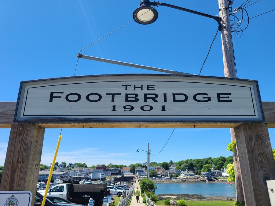 Downtown Boothbay Harbor waterfront with shops, docks and moored boats on a summer afternoon